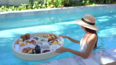 Güzel Asyalı bir kadının oteldeki havuzda dinlenirken çekilmiş görüntüleri.