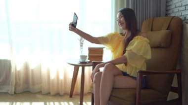 Güzel Asyalı kadının evde akıllı telefon kullandığının görüntüleri.