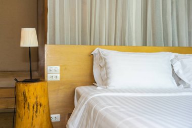 Yatak odasının içinde lamba süslemeli yastık ve battaniye.