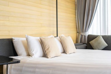 Otel odasındaki yatak odasının iç dekorasyonunda beyaz rahat yastık.