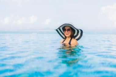 Güzel Asyalı genç kadınların portresi mutlu bir gülümseme tatil için tatil otelinde açık havuzda yüzme havuzu.