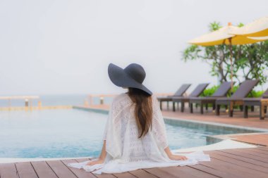 Asyalı genç bir kadının portresi mutlu bir gülümseme otel tatil beldesinde yüzme havuzunda rahatlamak