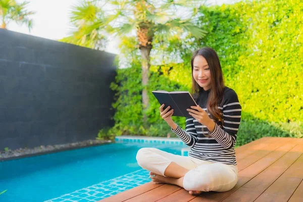 在酒店度假胜地的室外游泳池边 年轻的亚洲女子正在看书 — 图库照片