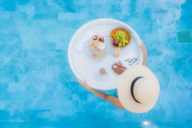 Güzel bir Asyalı kadın portresi. Öğleden sonra çayıyla ya da kahvaltısıyla otel havuzunda yüzer.