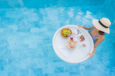 Güzel bir Asyalı kadın portresi. Öğleden sonra çayıyla ya da kahvaltısıyla otel havuzunda yüzer.