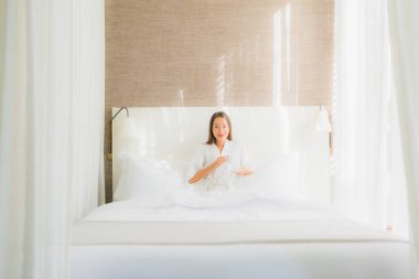 Güzel bir Asyalı kadın portresi. Mutlu bir gülümseme. Yatak odasının iç tarafında, kahve fincanı ile.