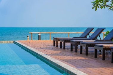 Otel tatil beldesinde açık havuz etrafında güzel boş sandalye şemsiyesi.