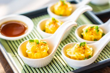 Beyaz kaşıkta soslu Çin buharlı karides köftesi.