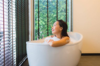 Güzel bir Asyalı kadın portresi mutlu bir gülümseme rahatla banyo küvetinde banyo yap.