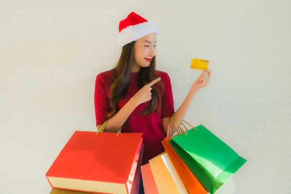 肖像画の美しい若いアジアの女性は ショッピングバッグスマート携帯電話とクレジットカードでクリスマスサンタの帽子を着用 — ストック写真