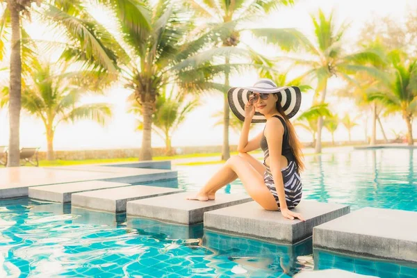日落时分或日出时分 亚洲年轻貌美的女子带着棕榈树在酒店度假胜地的室外游泳池中悠闲自在地游玩 — 图库照片