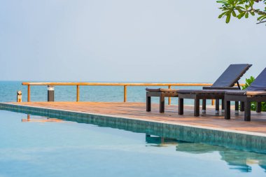 Otel tatil beldesinde açık havuz etrafında güzel boş sandalye şemsiyesi.