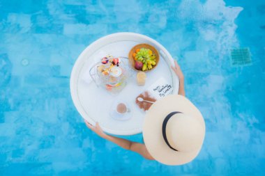 Güzel bir Asyalı kadın portresi. Öğleden sonra çayıyla ya da kahvaltısıyla otel havuzunda yüzer.