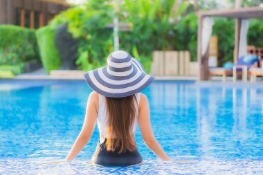 Güzel bir portre genç Asyalı mutlu bir gülümseme tatil beldesi otelinde havuzda rahatça yüzebiliyor.