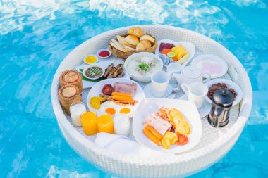 Kızarmış yumurta omletli, jambonlu, meyveli, sütlü kahveli ve yüzme havuzlu bir tepside yüzen kahvaltı.