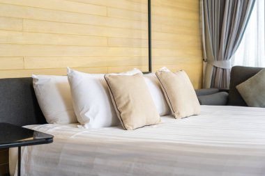 Otel odasındaki yatak odasının iç dekorasyonunda beyaz rahat yastık.