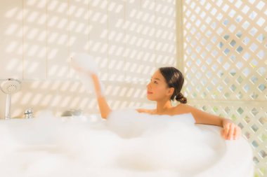 Portre genç Asyalı kadın rahatla spa konsepti için küvette banyo yap.
