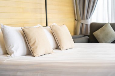 Otel odasındaki yatak odasının iç dekorasyonunda beyaz rahat yastık.