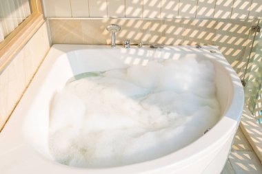 Banyonun içinde beyaz küvet ve jakuzi dekorasyonu var.