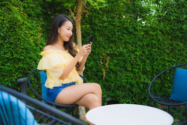 Genç Asyalı kadın açık hava manzarası için akıllı cep telefonu kullanıyor.