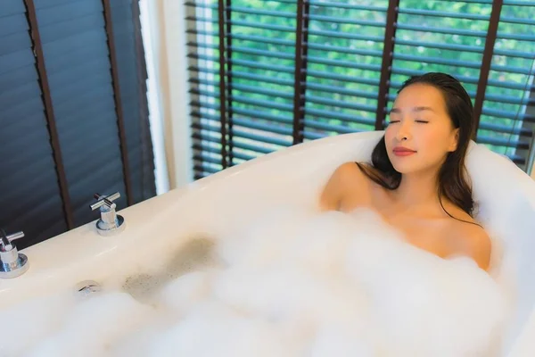 美丽动人的年轻亚洲女人快乐的微笑放松地在浴室的浴缸里洗澡 — 图库照片