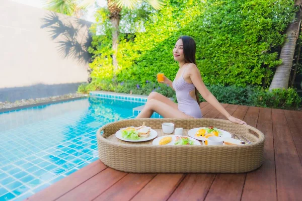 ポートレート若いアジアの女性幸せな笑顔は ホテルのリゾートでプールで浮遊朝食トレイでお楽しみください — ストック写真