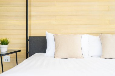 Otel odasındaki yatak odasının iç dekorasyonunda beyaz rahat yastık.