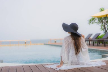 Asyalı genç bir kadının portresi mutlu bir gülümseme otel tatil beldesinde yüzme havuzunda rahatlamak