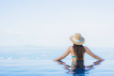 Güzel Asyalı genç kadınların portresi mutlu bir gülümseme tatil için tatil otelinde açık havuzda yüzme havuzu.
