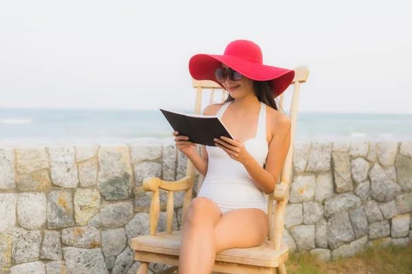 Portrait young asian woman read book around beach sea ocean in travel vacation