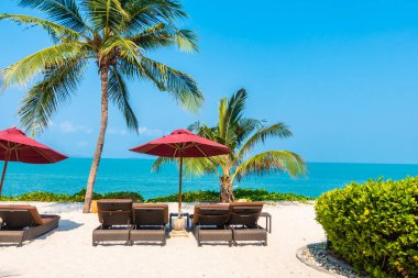 Güzel tropikal deniz okyanusu, şemsiyesi ve sandalyesi ile mavi gökyüzünde hindistan cevizi palmiyesinin etrafında tatil için