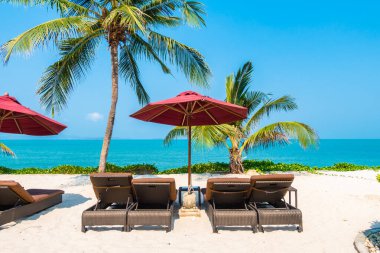 Güzel tropikal deniz okyanusu, şemsiyesi ve sandalyesi ile mavi gökyüzünde hindistan cevizi palmiyesinin etrafında tatil için