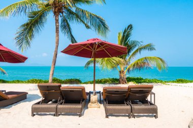 Güzel tropikal deniz okyanusu, şemsiyesi ve sandalyesi ile mavi gökyüzünde hindistan cevizi palmiyesinin etrafında tatil için