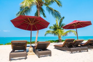 Güzel tropikal deniz okyanusu, şemsiyesi ve sandalyesi ile mavi gökyüzünde hindistan cevizi palmiyesinin etrafında tatil için