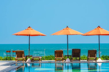 Şemsiye ve sandalye açık havuz etrafında. Tatil tatili için otel odasında deniz yok.