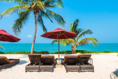 Güzel tropikal deniz okyanusu, şemsiyesi ve sandalyesi ile mavi gökyüzünde hindistan cevizi palmiyesinin etrafında tatil için