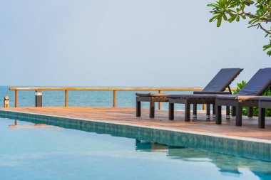 Otel tatil beldesinde açık havuz etrafında güzel boş sandalye şemsiyesi.