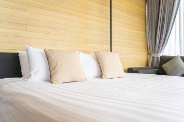 Otel odasındaki yatak odasının iç dekorasyonunda beyaz rahat yastık.