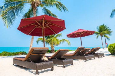 Güzel tropikal deniz okyanusu, şemsiyesi ve sandalyesi ile mavi gökyüzünde hindistan cevizi palmiyesinin etrafında tatil için