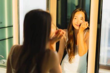 Güzel bir Asyalı kadın portresi makyaj malzemesi makyaj malzemesi ve yüz makyajı ile banyo içinde yüz maskesi.