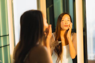 Güzel bir Asyalı kadın portresi. Banyo içinde yüzüne ve yüzüne krem sür.