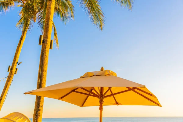 夕日や旅行休暇のための日の出でビーチの海の周りのヤシの木と美しい熱帯の自然傘の椅子 — ストック写真