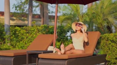 Güzel Asyalı bir kadının havuz kenarında güneşlendiği görüntüler.