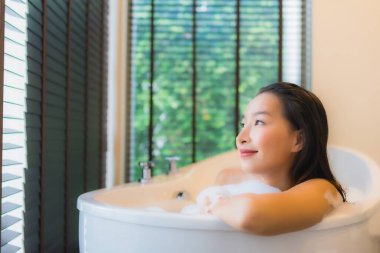 Güzel bir Asyalı kadın portresi mutlu bir gülümseme rahatla banyo küvetinde banyo yap.
