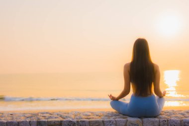 Genç Asyalı kadının portresi sağlık için gün doğumunda deniz kıyısı okyanusunda meditasyon yapıyor.