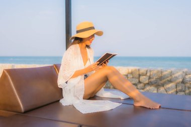 Portre genç Asyalı kadın seyahat tatilinde deniz kenarında kitap okudu.