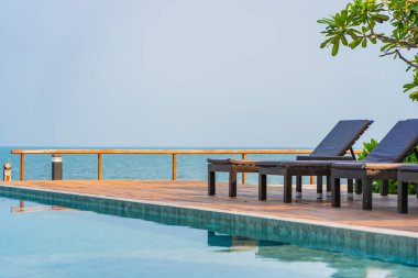 Otel tatil beldesinde açık havuz etrafında güzel boş sandalye şemsiyesi.