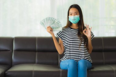 Maskeli güzel Asyalı kadının portresi evde para ya da para gösteriyor.