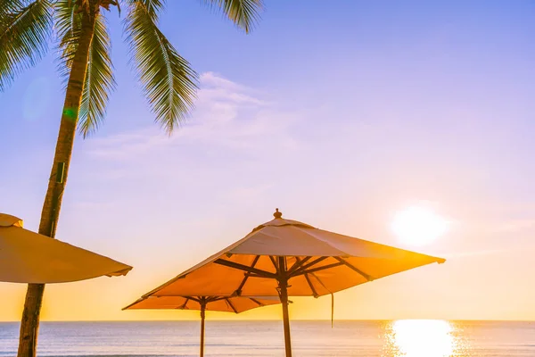 夕日や旅行休暇のための日の出でビーチの海の周りのヤシの木と美しい熱帯の自然傘の椅子 — ストック写真