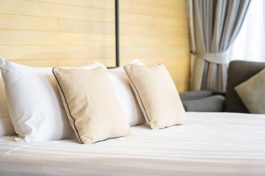 Otel odasındaki yatak odasının iç dekorasyonunda beyaz rahat yastık.
